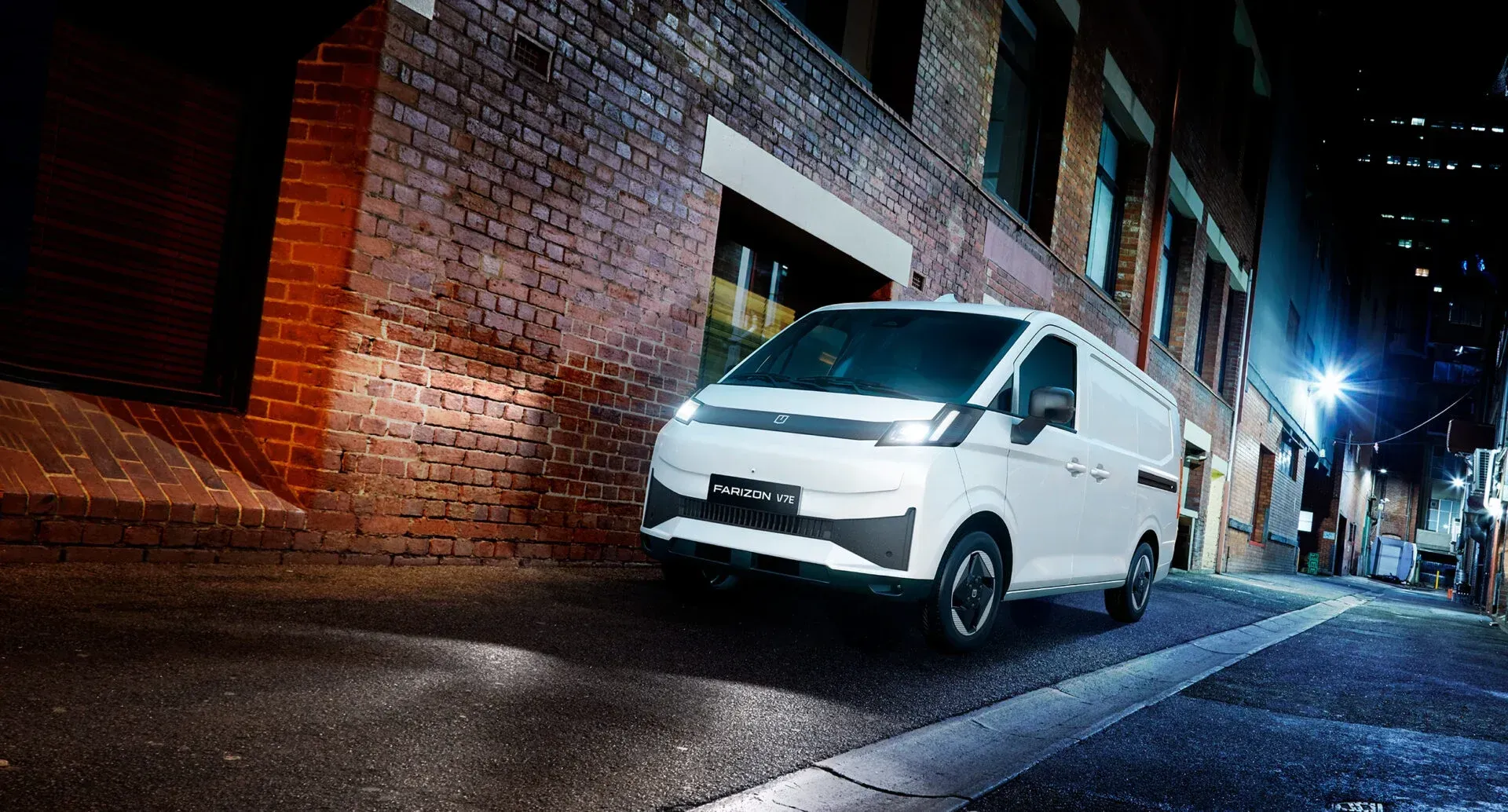 A side view of a light blue minivan parked on a paved lot with trees and a building in the background.