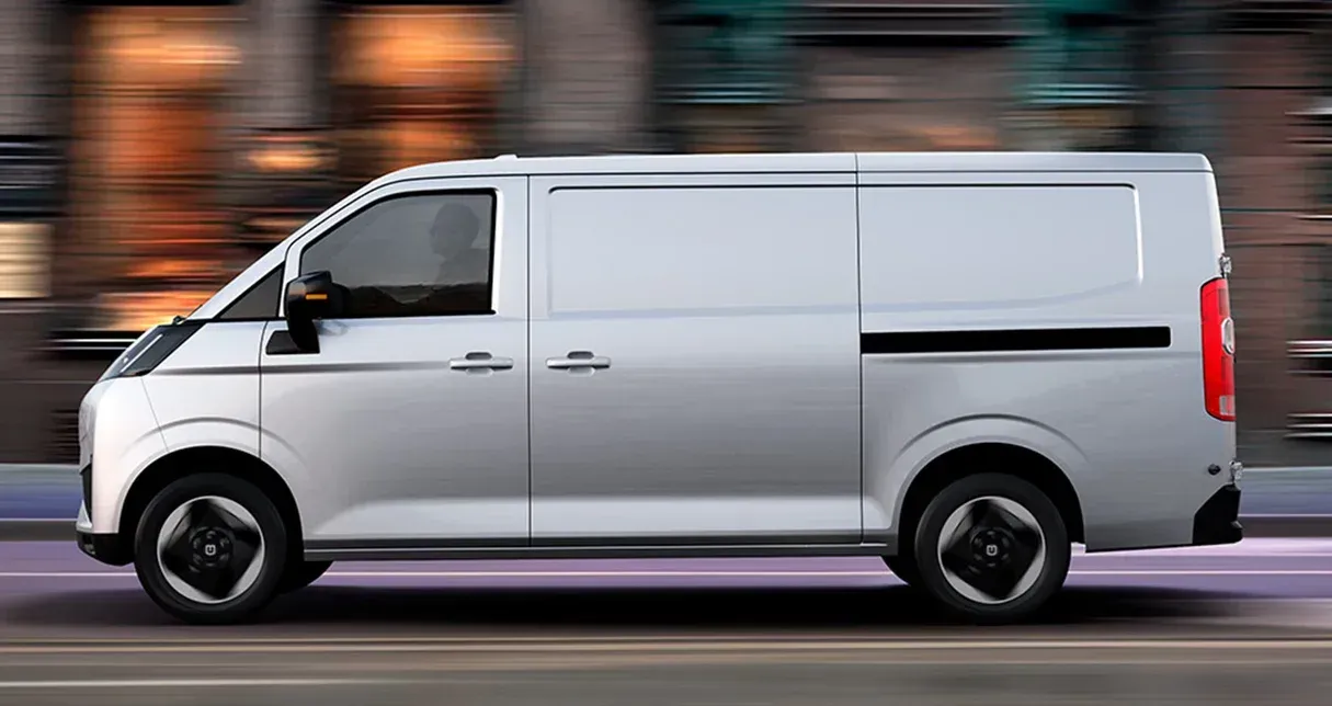 A silver cargo van driving on a city street, captured with a motion blur effect.