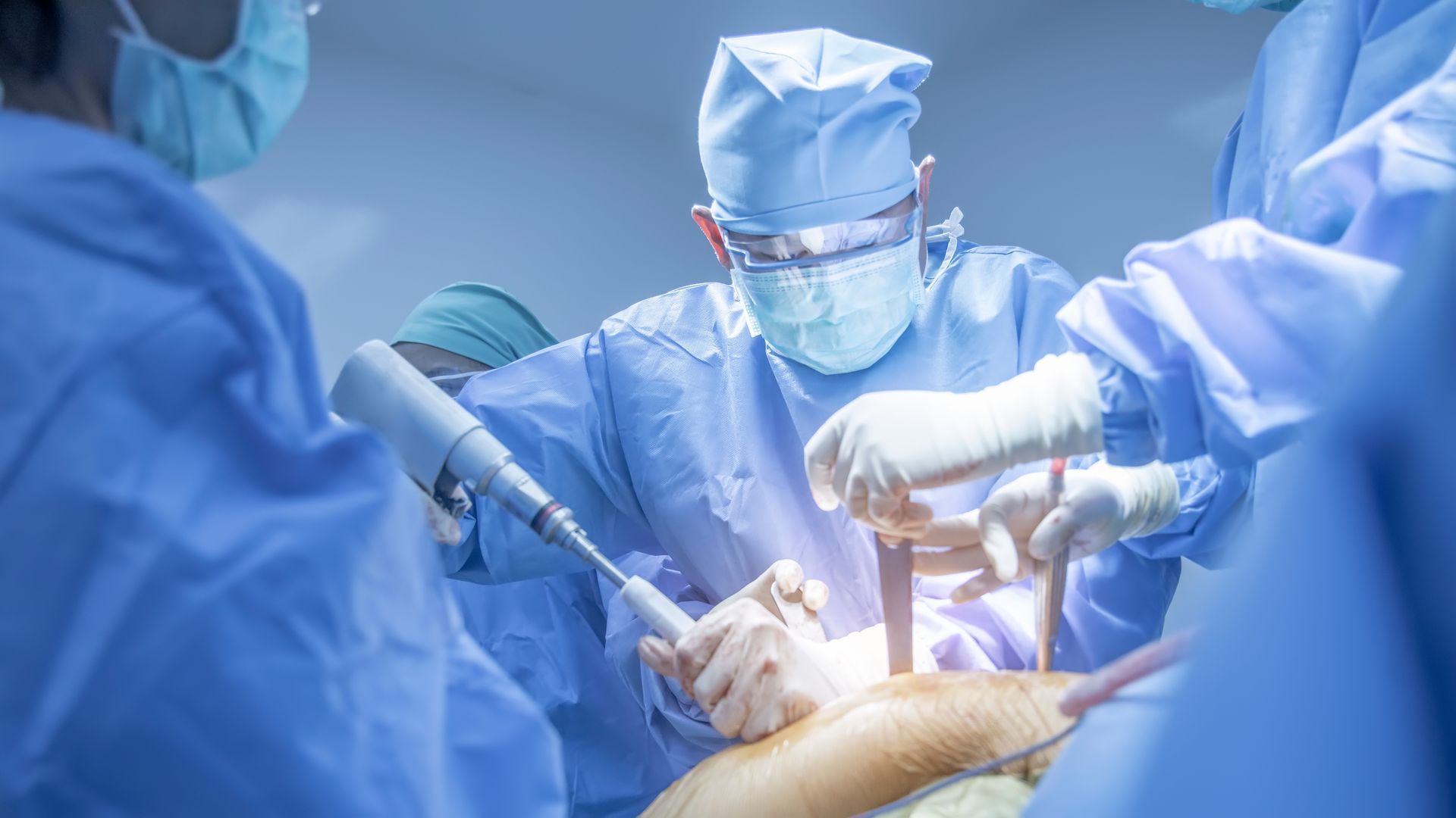 A team of orthopedic surgeons performing surgery on a patient in a sterile operating room.