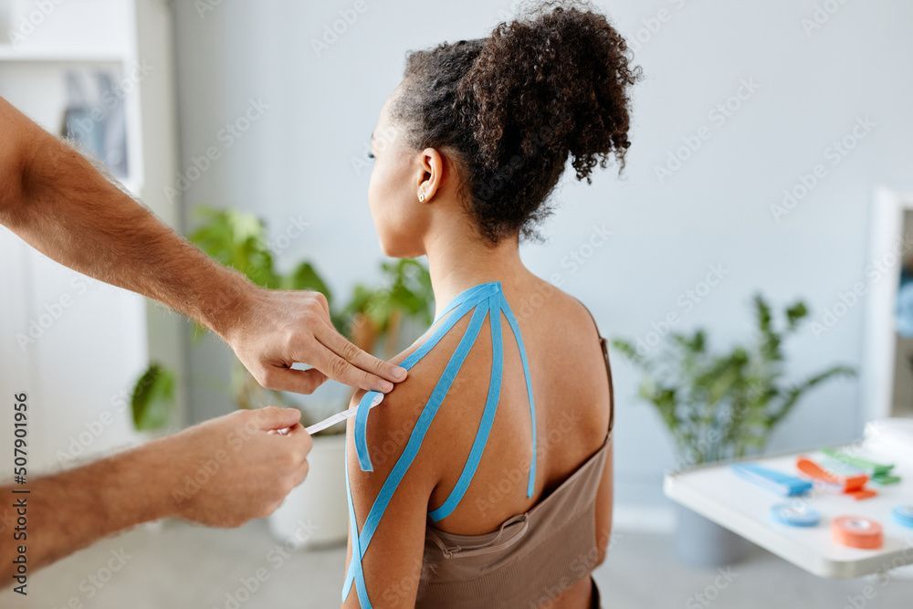 Physical therapist helping young black woman with her shoulders.