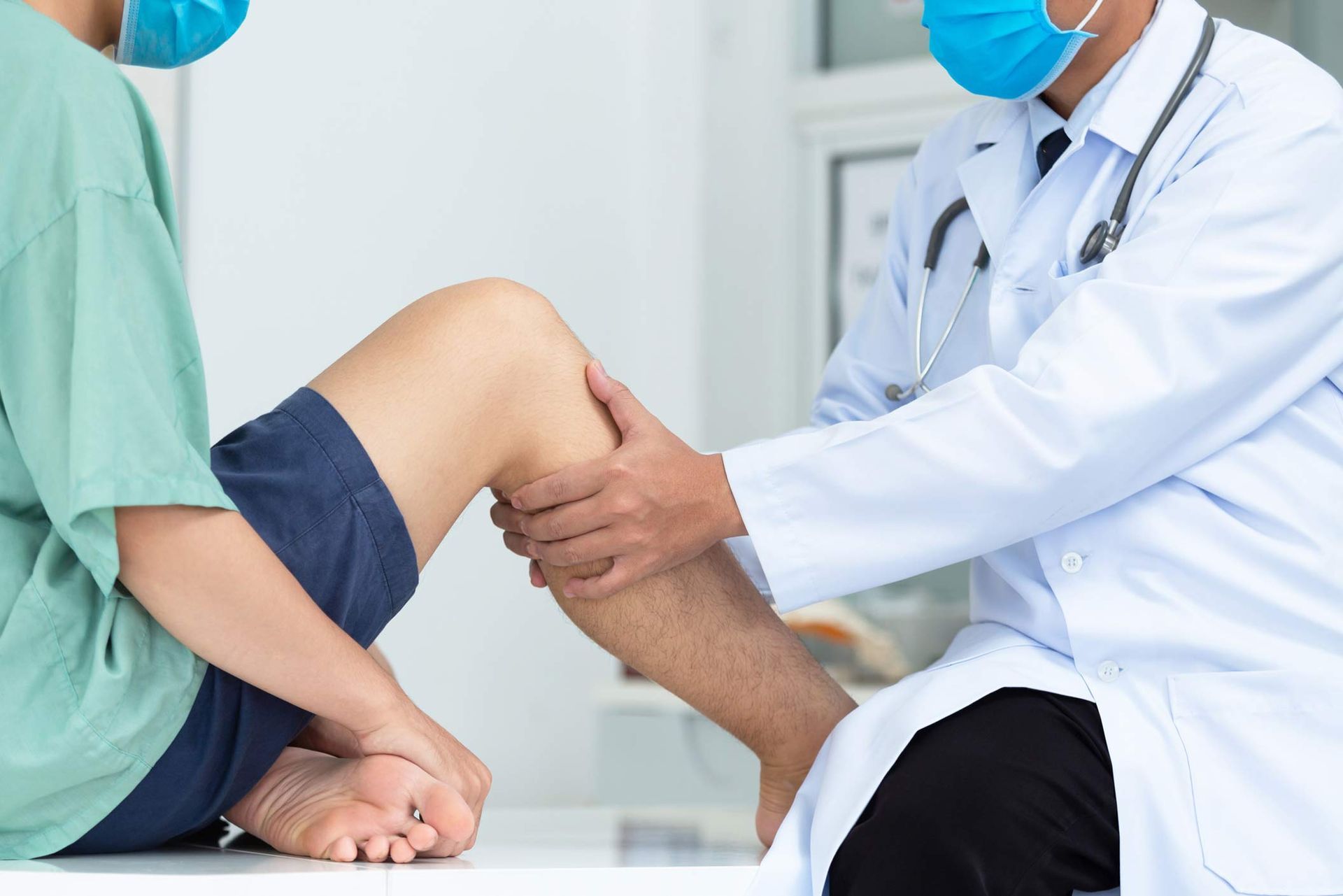 A sports injury physician assessing a patient with knee pain during a clinical consultation.