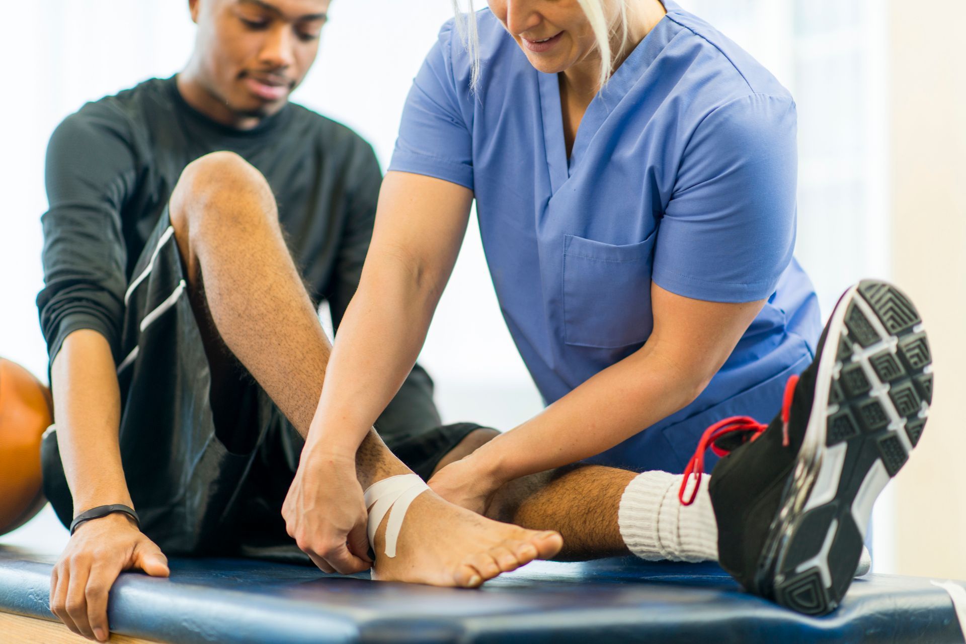 A person with a bandaged ankle receives care from a medical professional.