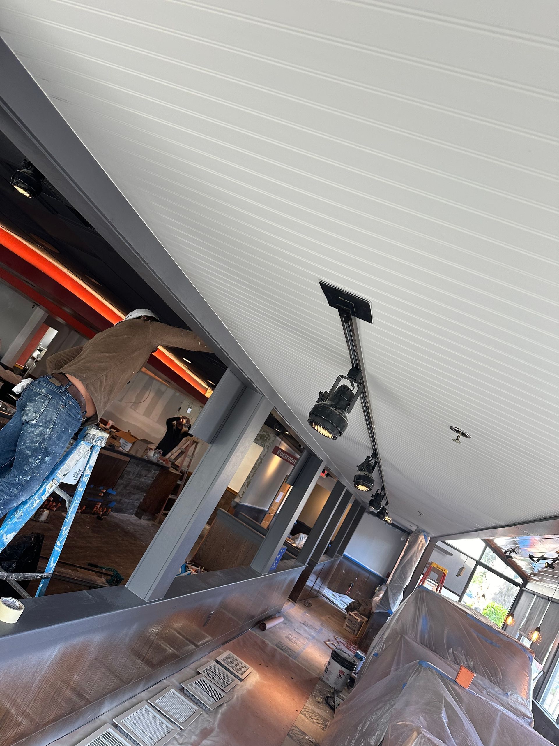 Two people hold paint swatch cards against a white wall, choosing paint colors.