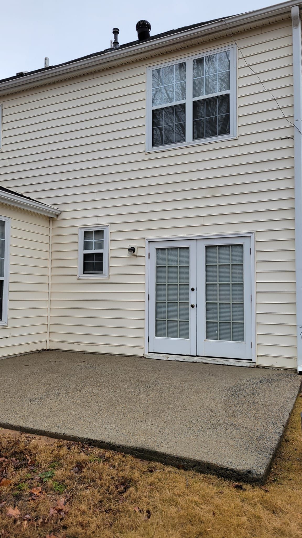 The back of a house with a patio and sliding glass doors.