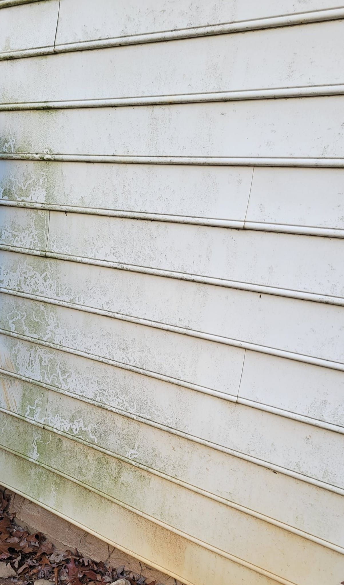 A close up of a dirty white siding on a house.