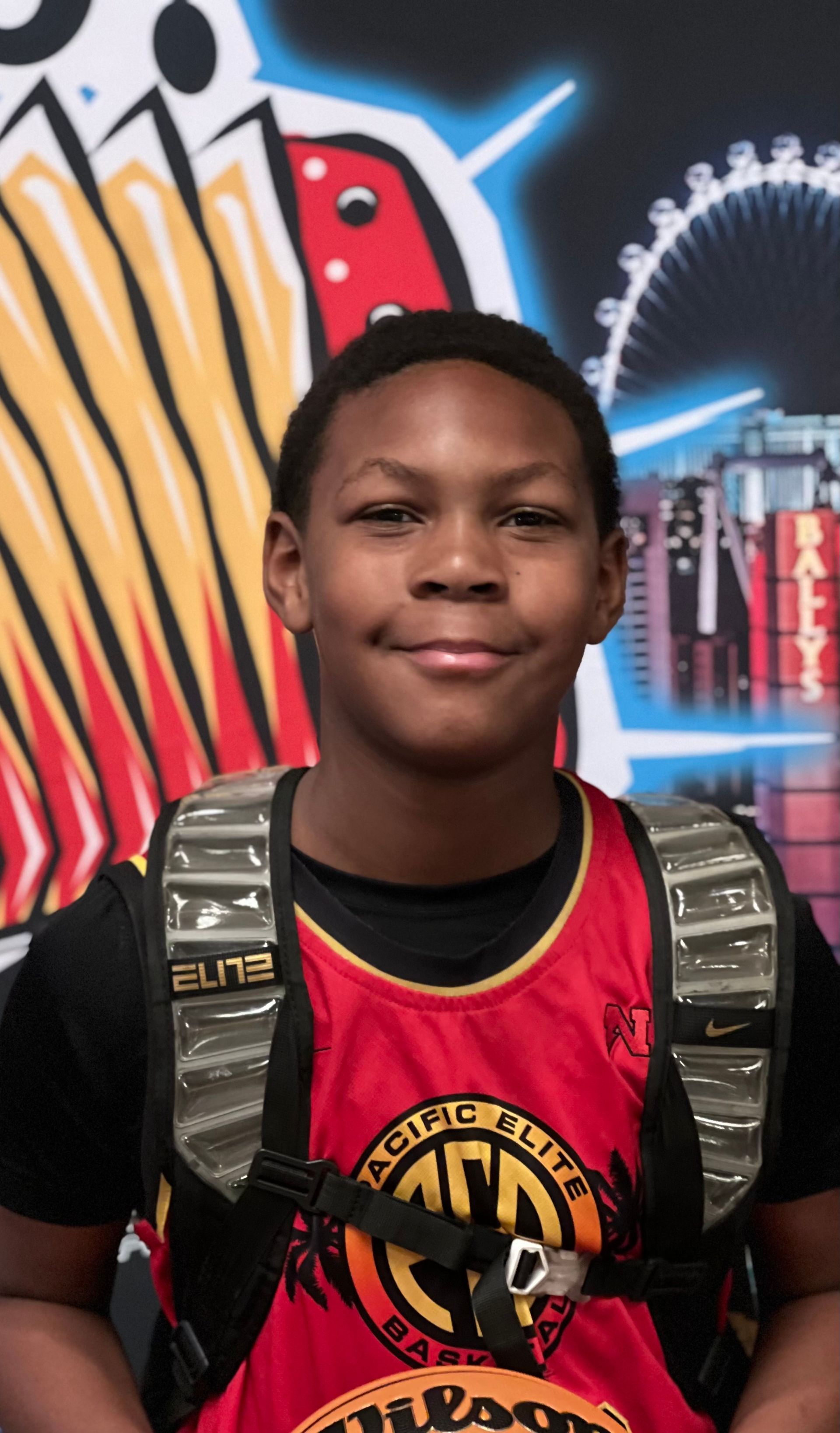 Woman with long, dark braids, in a sparkly blue dress, smiling in front of a gold backdrop.