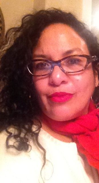 A woman wearing glasses and a red scarf is smiling for the camera.