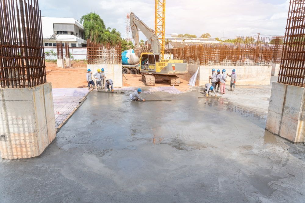 A Group Of Construction Workers Are Working On A Concrete Floor At A Construction — Neil Stafford Concreting In Mareeba, QLD