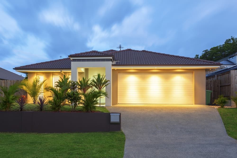 A house with a large garage door is lit up at night. — Andrew Logan Building In Dubbo, NSW