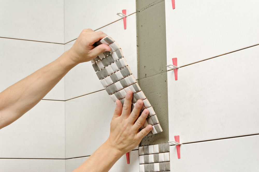A Person Is Installing Tiles On A Wall — Andrew Logan Building In Gilgandra, NSW