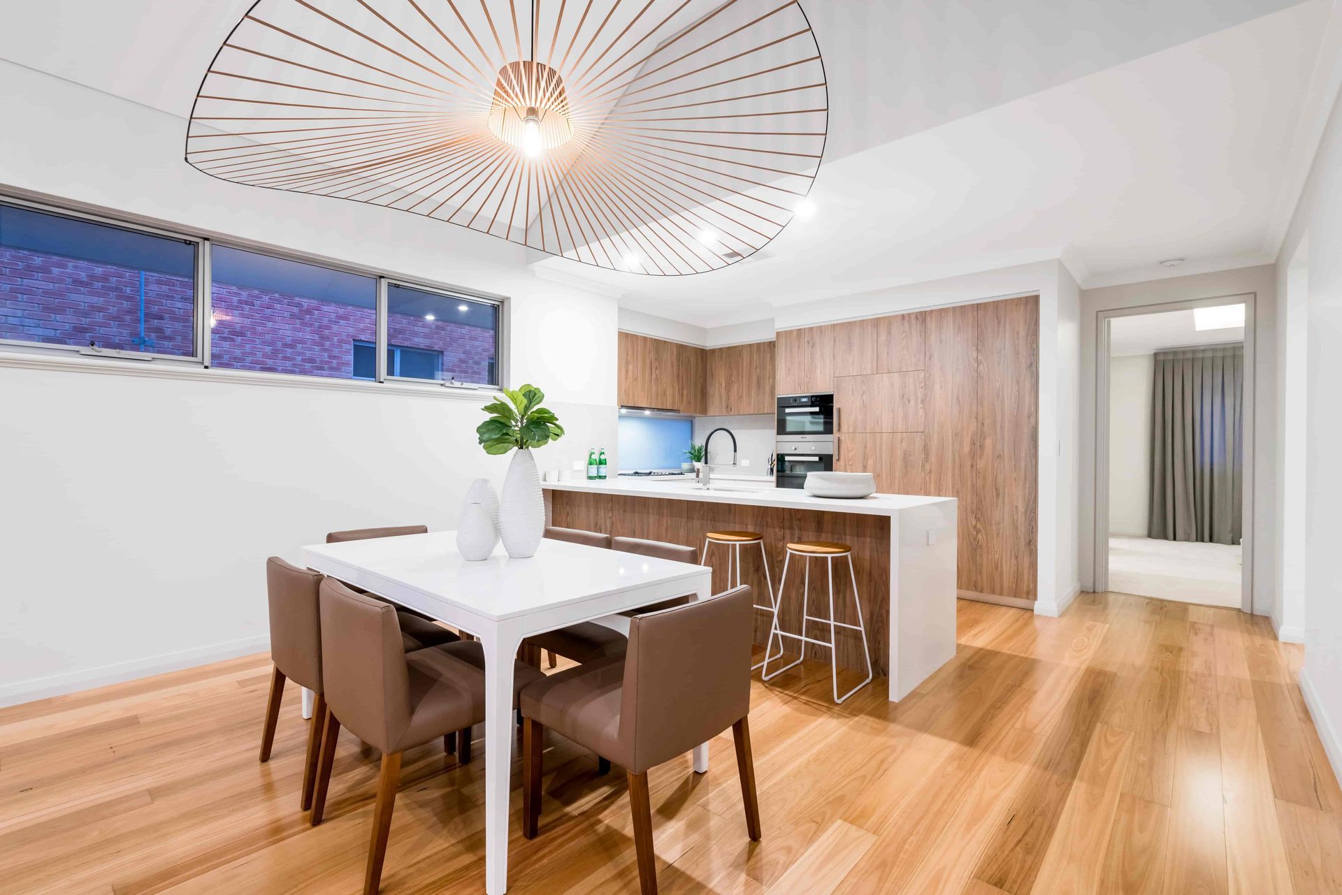 A dining room with a table and chairs and a kitchen in the background. — Andrew Logan Building In Dubbo, NSW