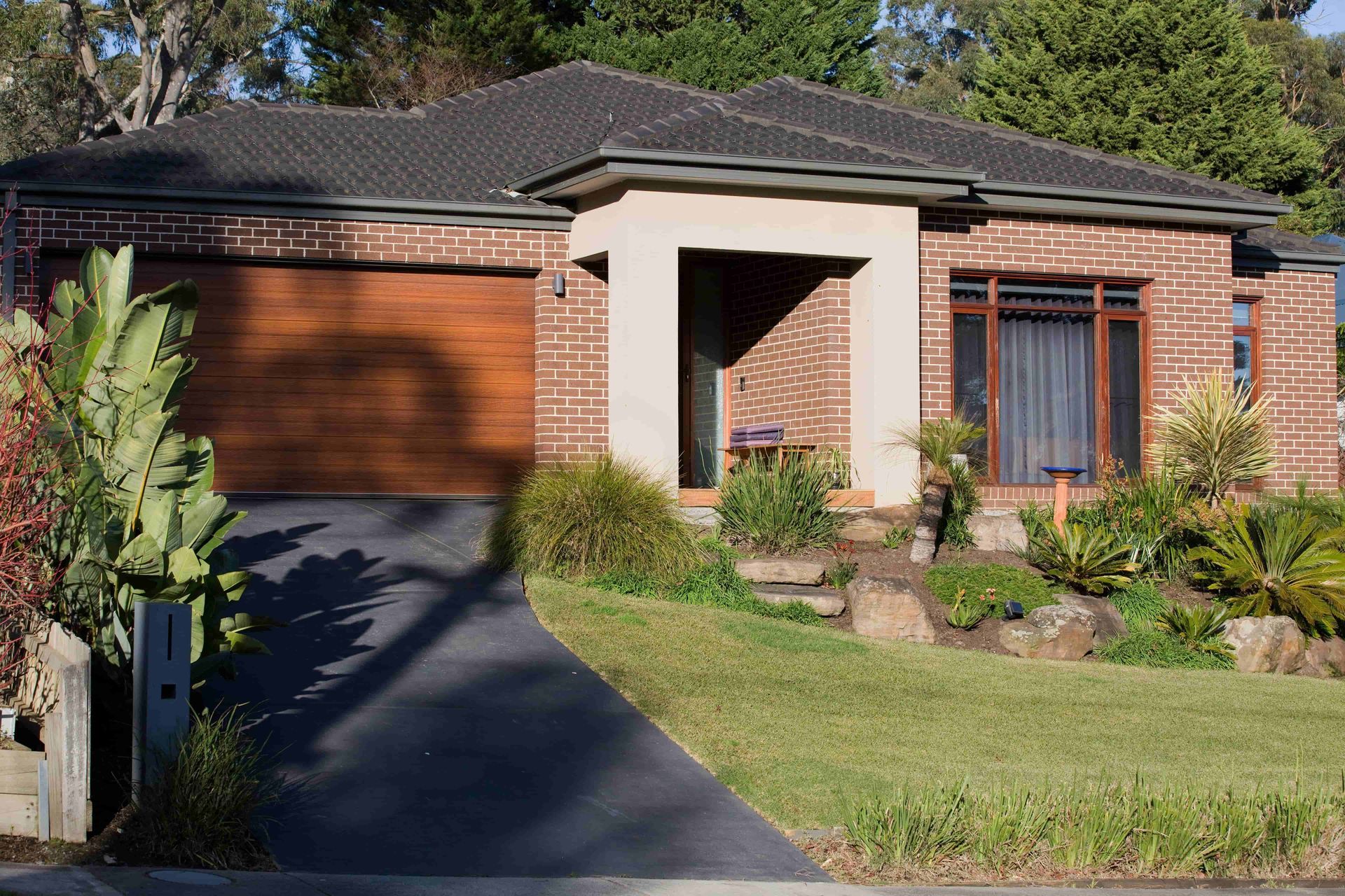 A brick house with a wooden garage door — Andrew Logan Building In Narromine, NSW