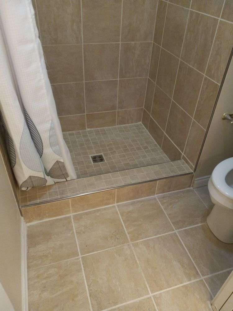 Bathroom shower with beige tile, shower curtain, and toilet.