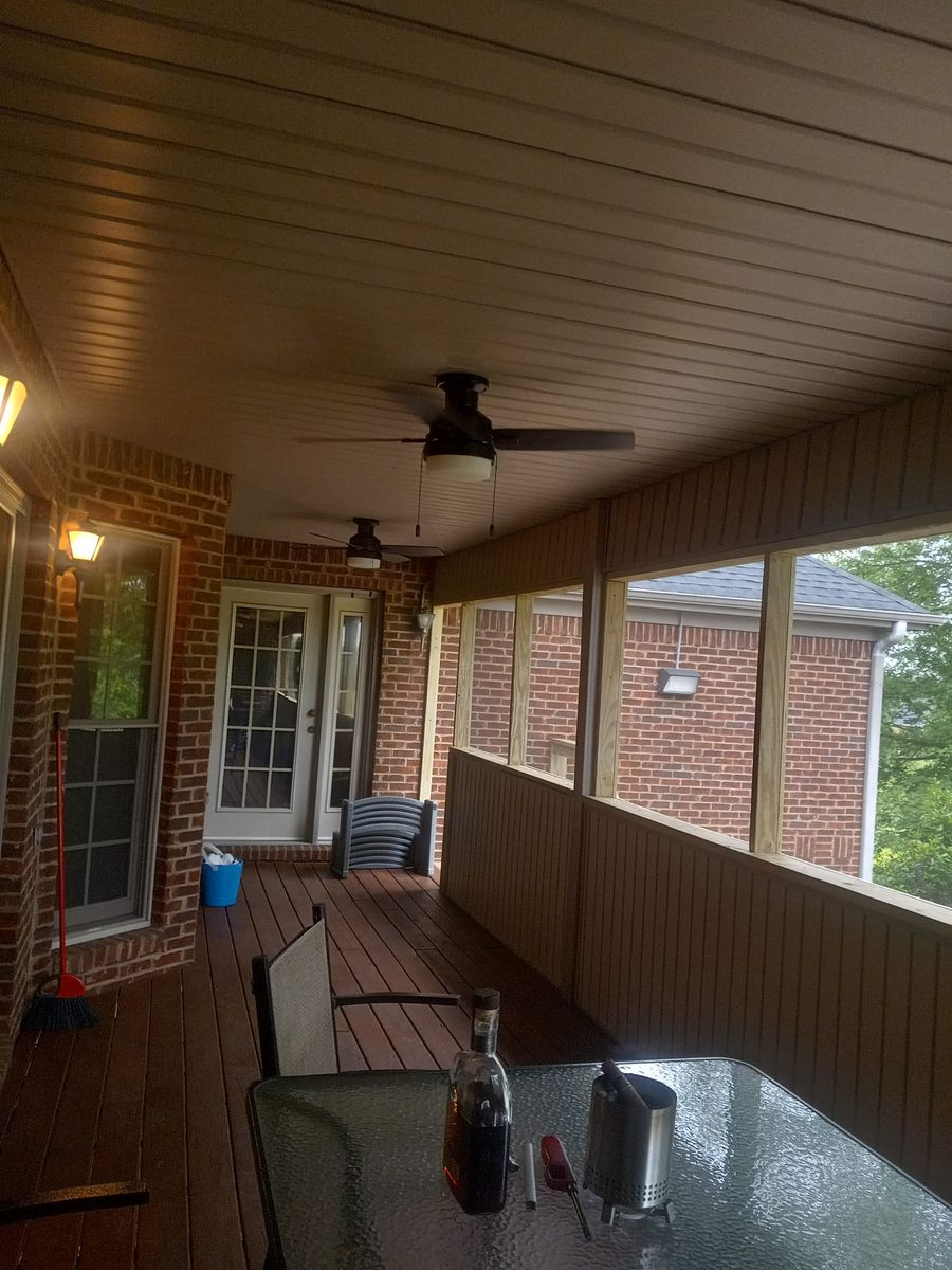 Covered porch with ceiling fans, red brick walls, wooden deck, and furniture.