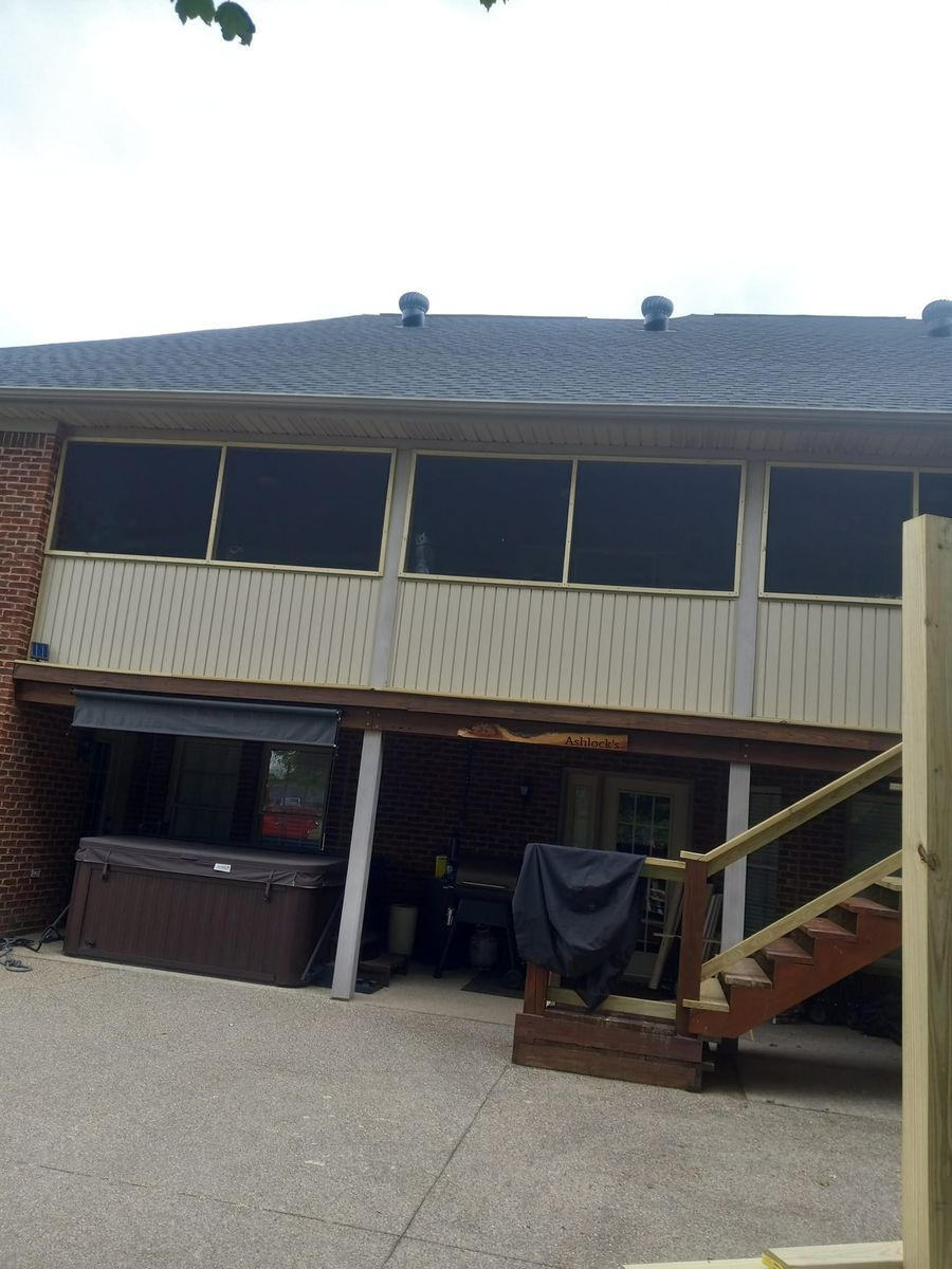 Brick house with screened porch, hot tub, and wooden deck.