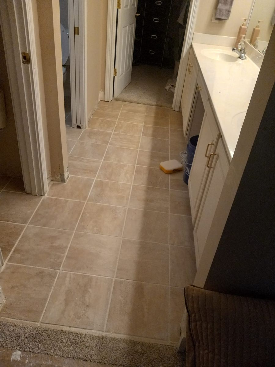 Hallway with beige tile floor, white vanity, and open doors.