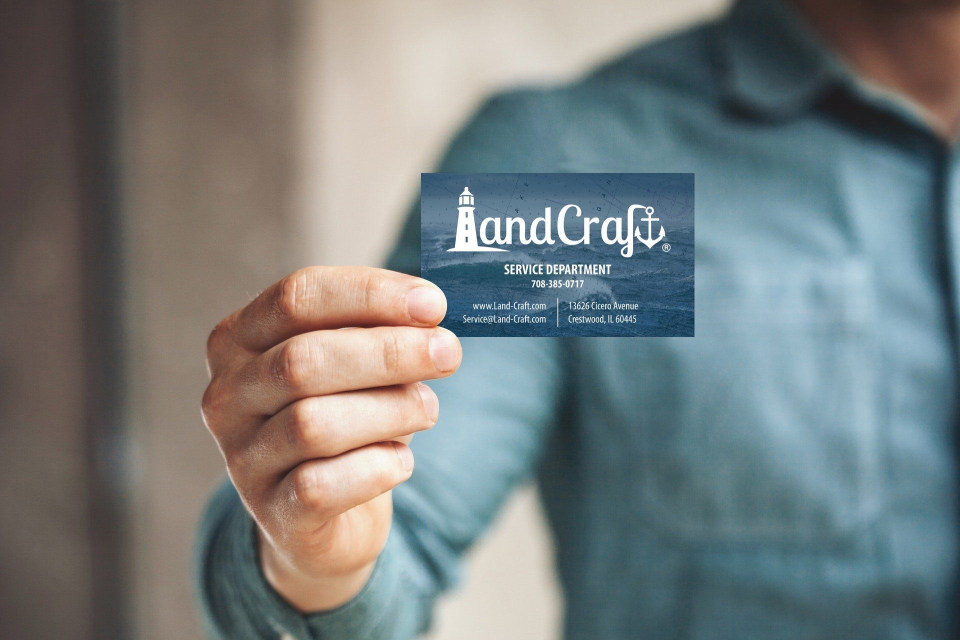 Person holding up a LandCraft business card designed by SmallBee