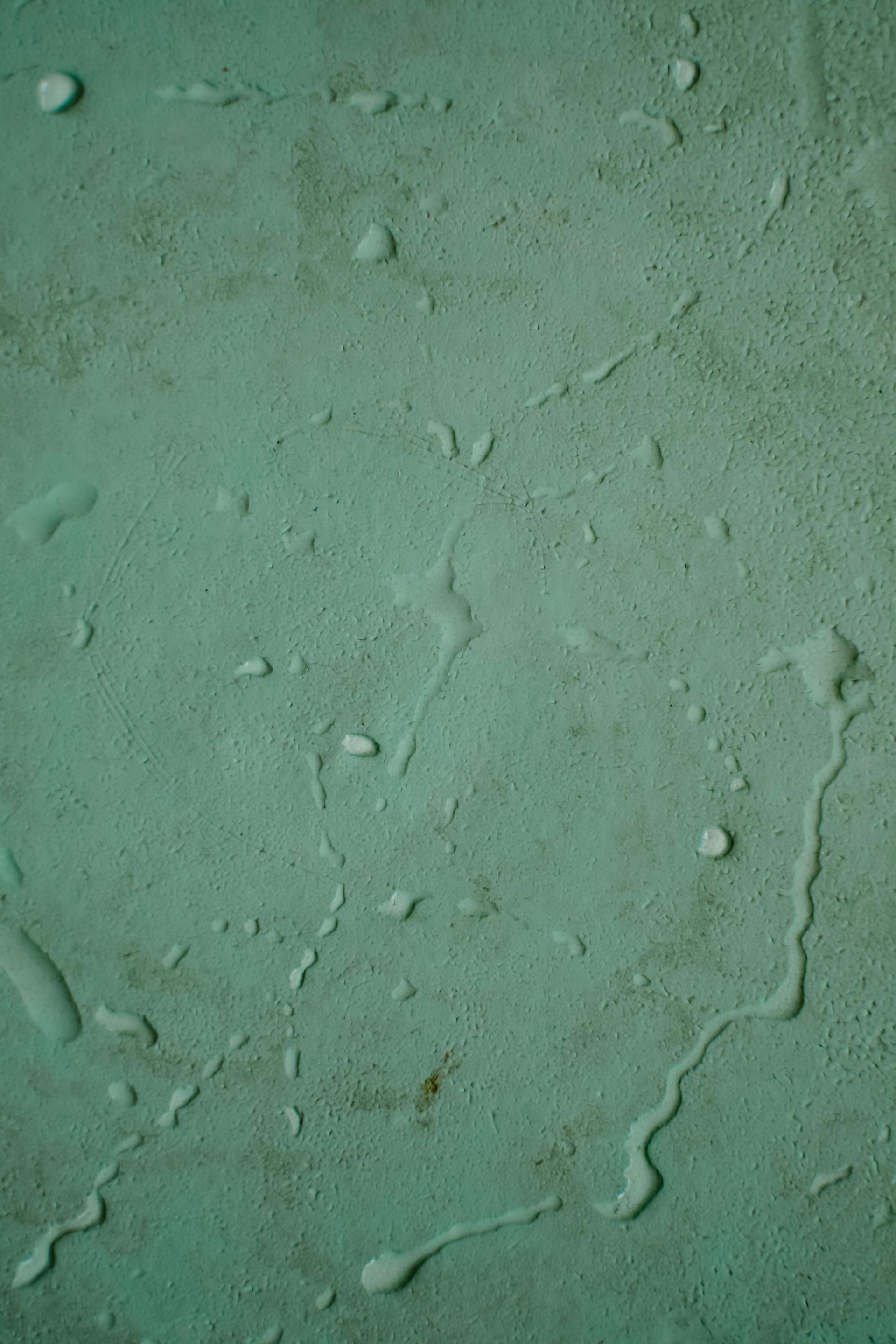 Green surface with water droplets and streaks.