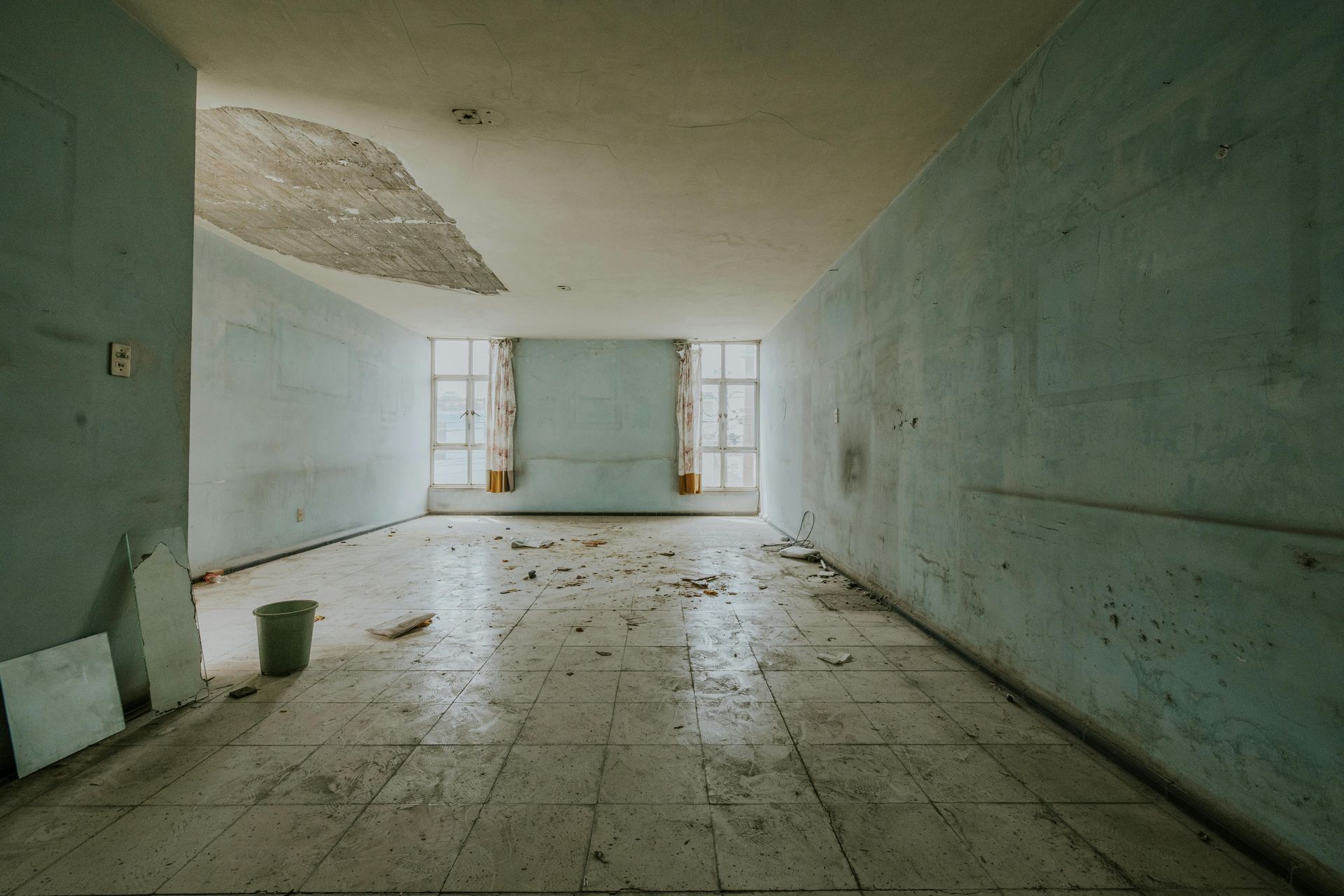 Interior of a room with severe mold damage on the walls. Window is in the center.