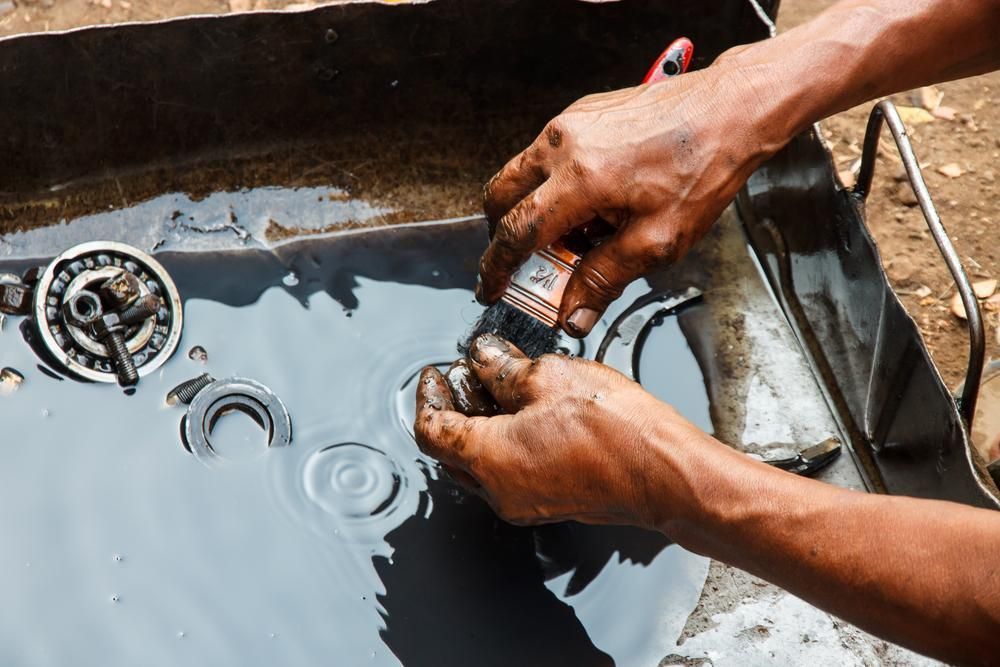 A Man Is Cleaning A Motorcycle Engine With A Brush — Torque Tech Supply & Repairs In Coffs Harbour, NSW