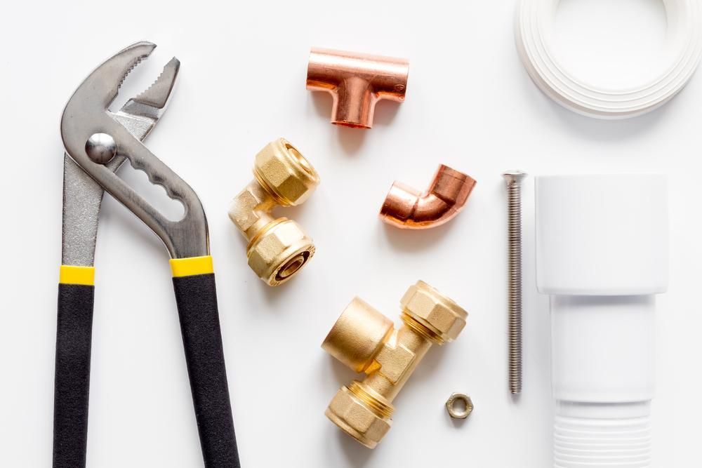 A Pair Of Pliers , Copper Pipes , And Screws On A White Surface — Torque Tech Supply & Repairs In South West Rocks, NSW