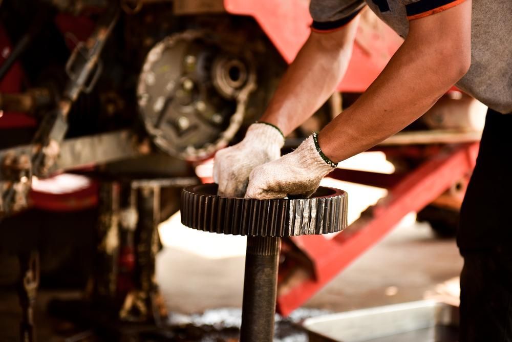 A Man Is Working On A Gear On A Vehicle In A Garage — Torque Tech Supply & Repairs In Port Macquarie, NSW