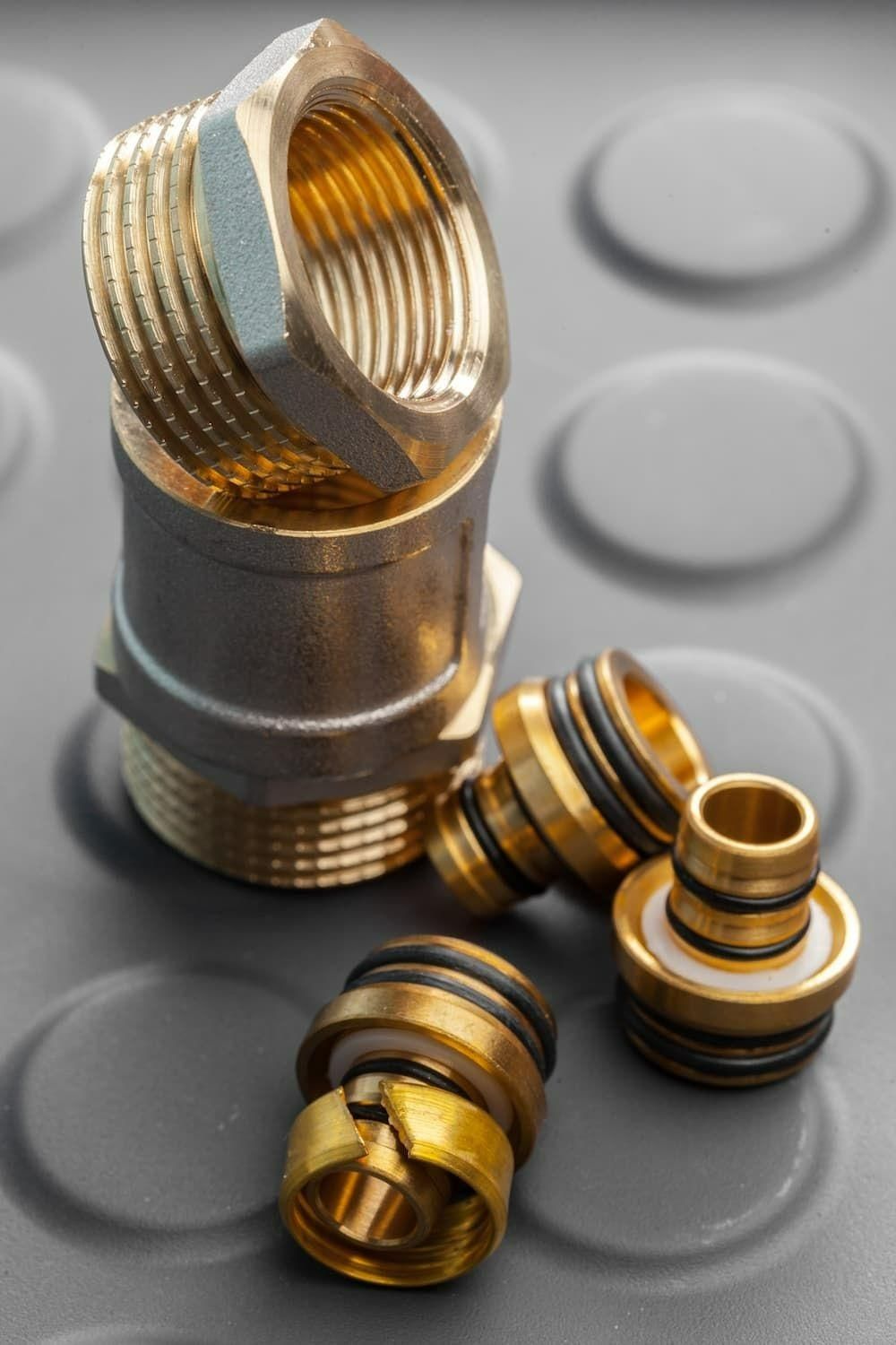 A Bunch Of Brass Fittings Are Stacked On Top Of Each Other On A Rubber Mat — Torque Tech Supply & Repairs In Taree, NSW