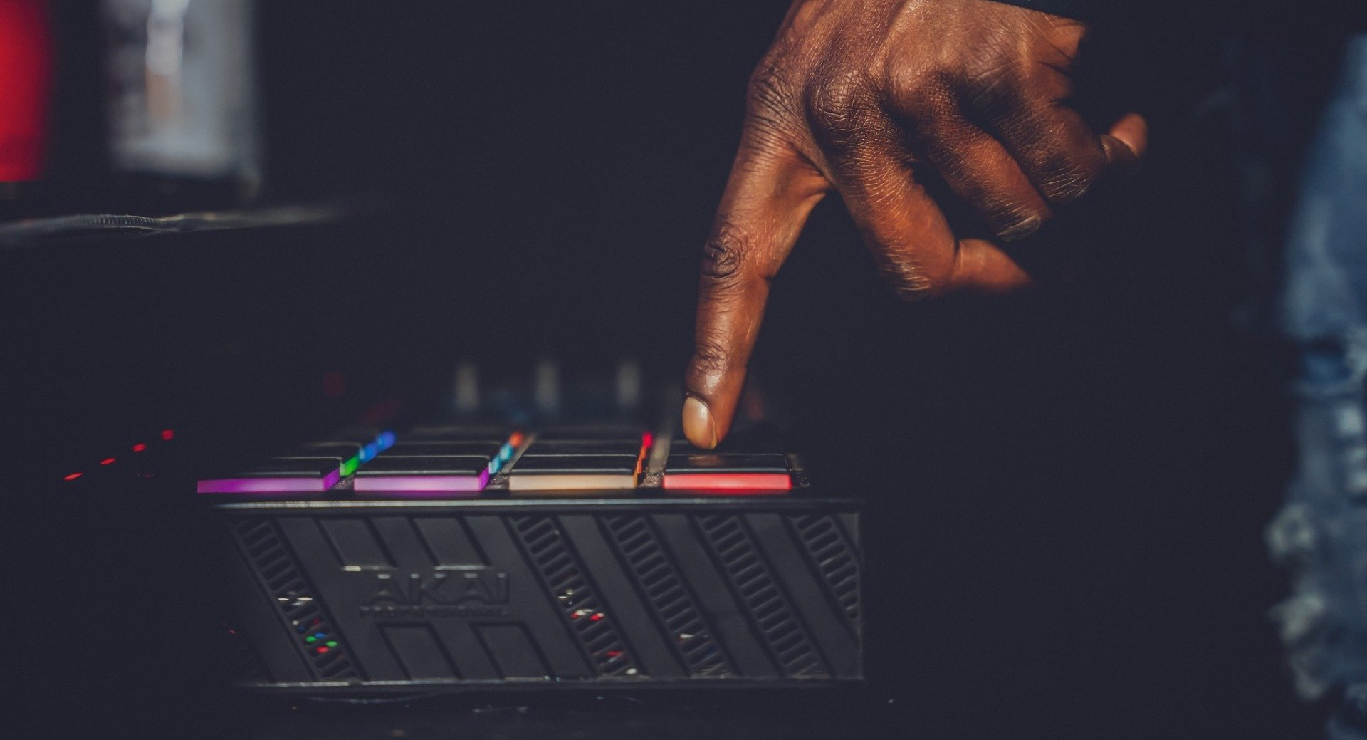 Close-up of a hand pressing a button on a black device with colorful lights.