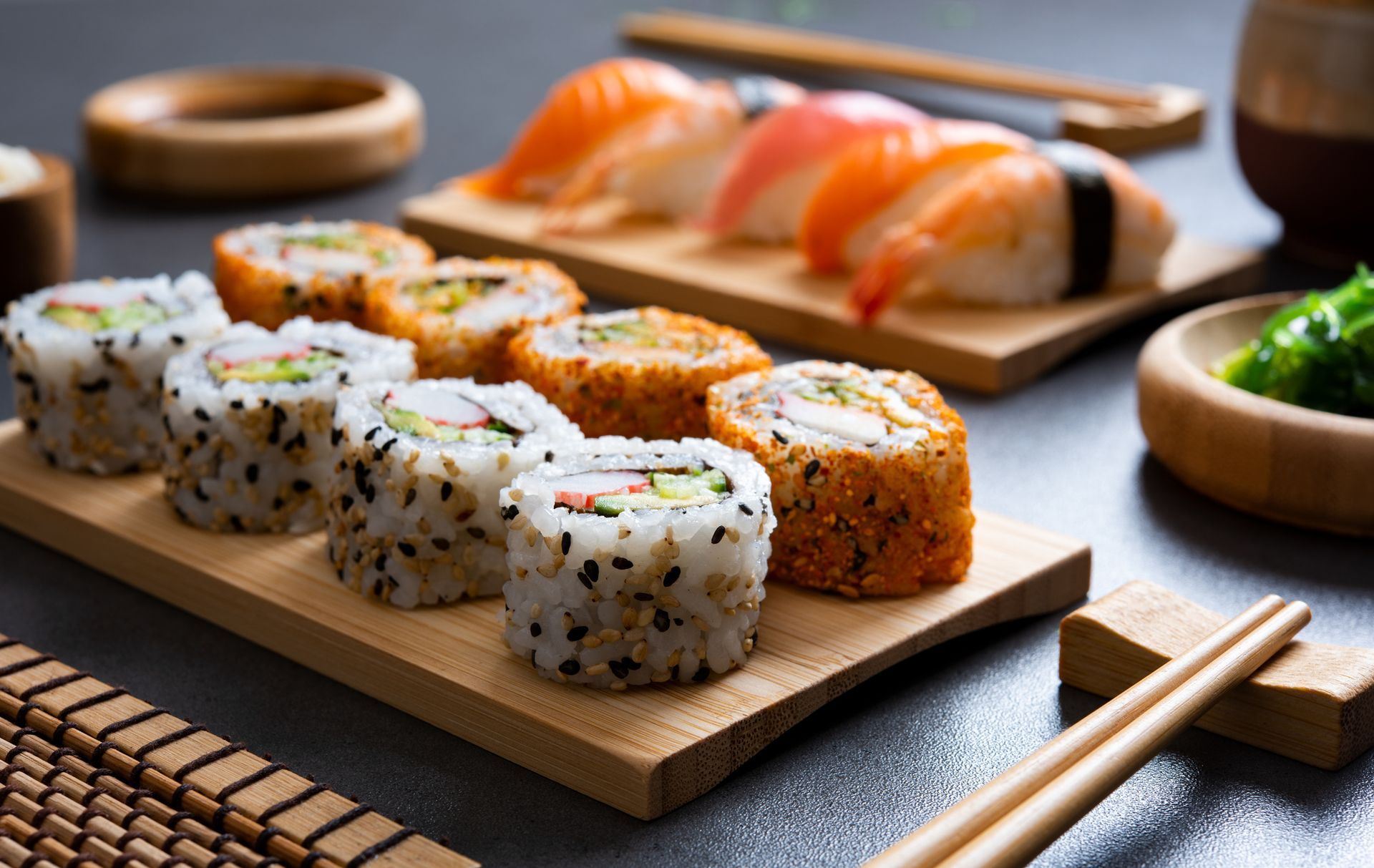 Various kinds of sushi pieces are served on a plate with wooden chopsticks at a sushi restaurant.