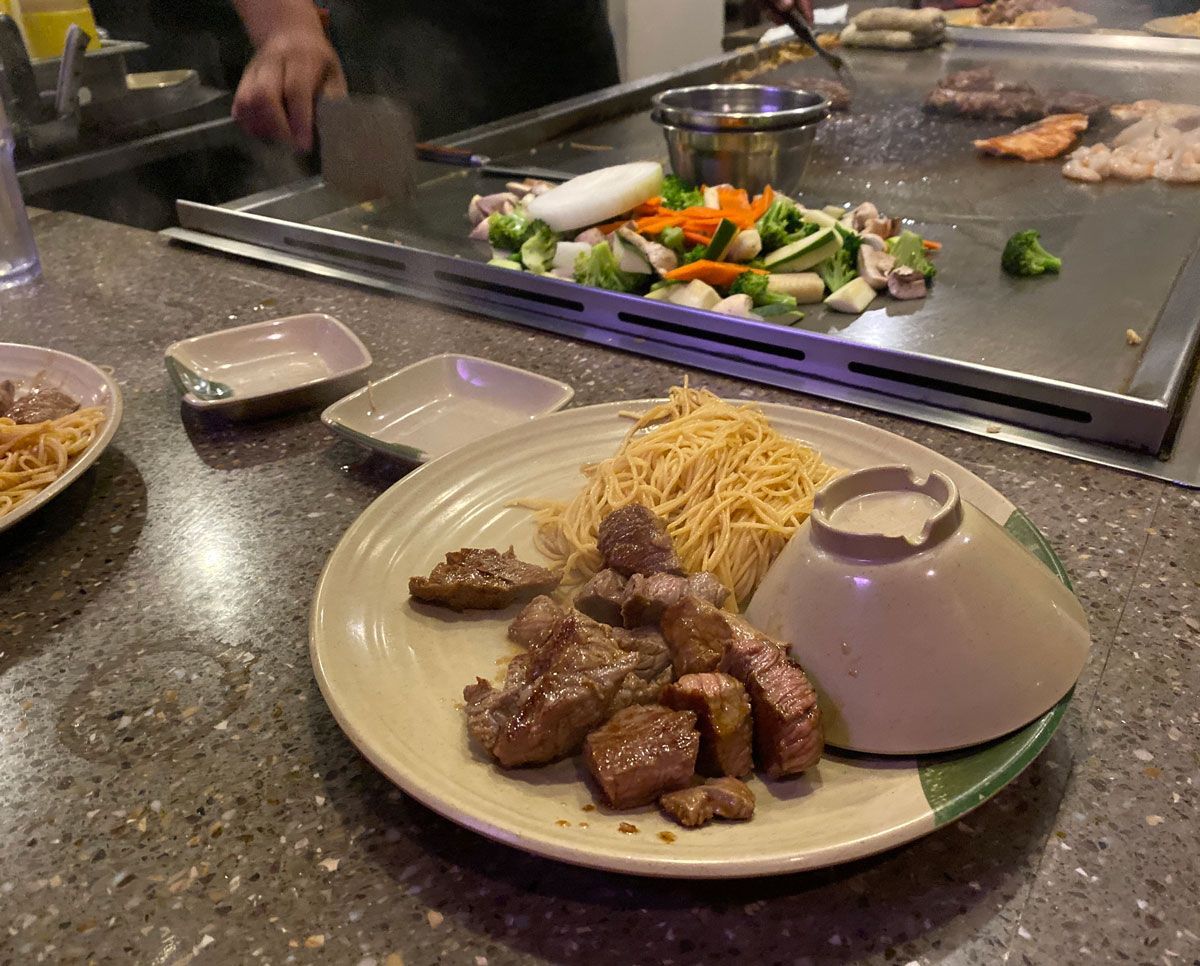 A plate of food with noodles and meat on a table in a restaurant.