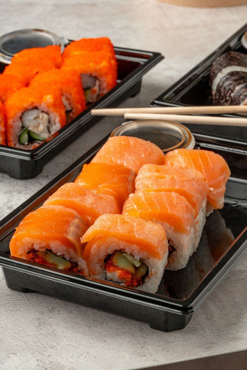 A close up of a tray of sushi with chopsticks on a table.