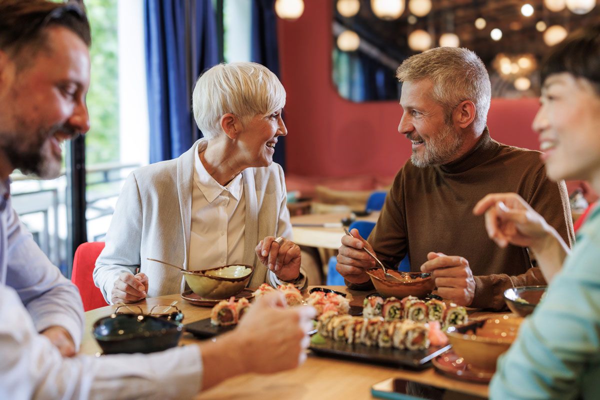 A group of people are sitting at a table in a restaurant eating sushi.