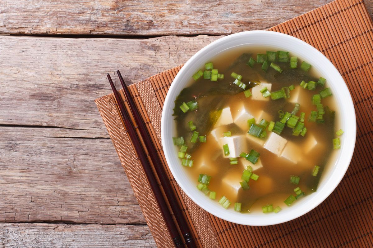 A bowl of soup with chopsticks on a wooden table.