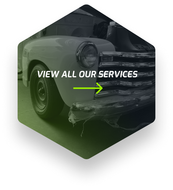 An old white truck is parked in a garage in a hexagon. | Galindo's Garage
