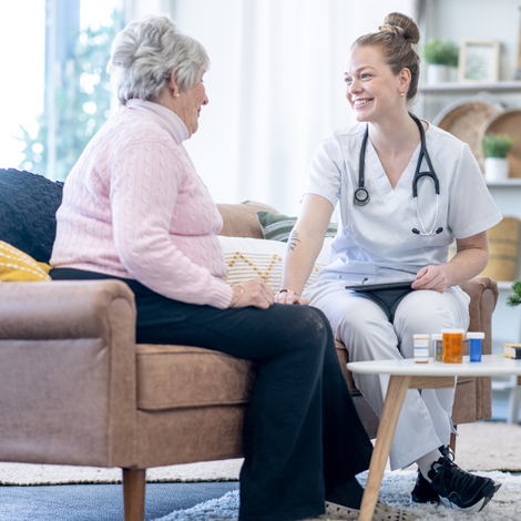 A nurse is helping an elderly woman with a walker.