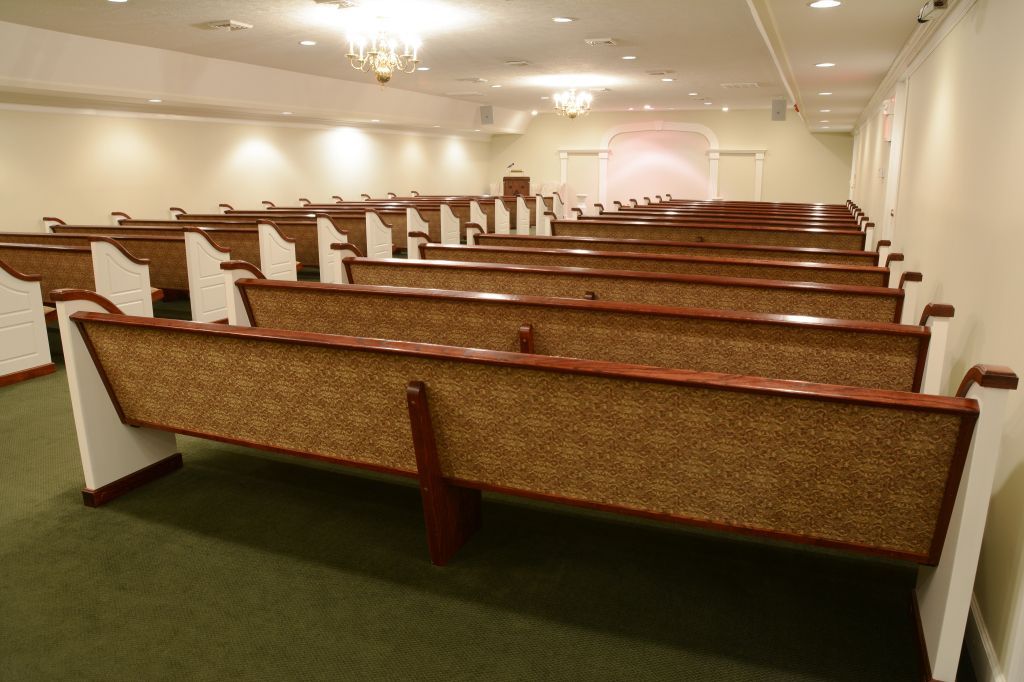 Rows of wooden benches in a church with a green carpet