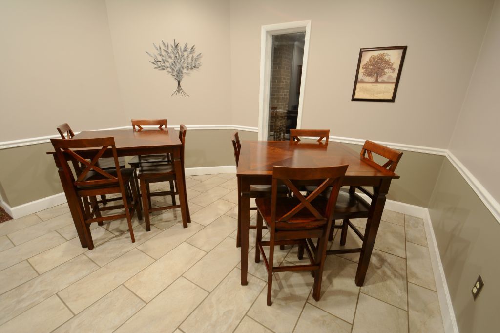 A dining room with a table and chairs and a tree on the wall