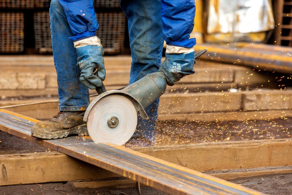 A man is cutting a piece of metal with a grinder.