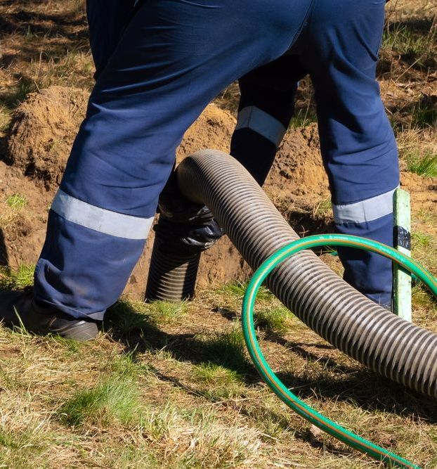 A Man in Blue Pants is Standing Next to a Large Hose — Puzzles Plumbing & Excavations In Koonorigan, NSW