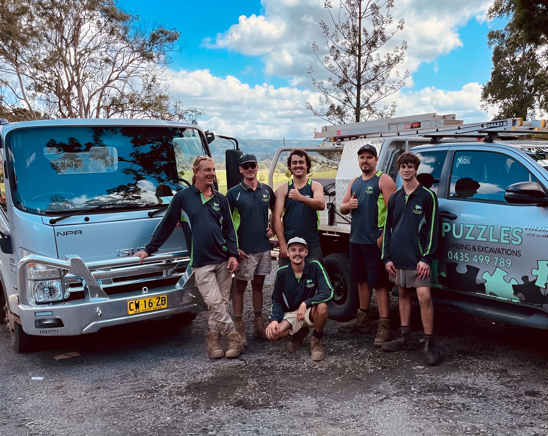 A Group Of Six Workers standing In Front Of A Ute And Truck — Puzzles Plumbing & Excavations In Koonorigan, NSW