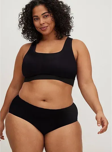 A plus size woman is wearing a black bra and underwear