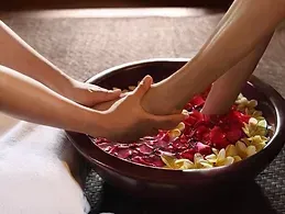 A woman is getting her feet massaged in a bowl of water and flowers