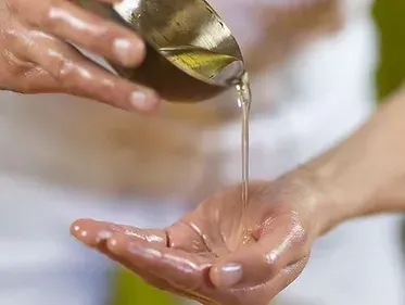 A person is pouring oil into another person 's hand