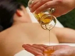 A person is pouring oil on another person 's hand