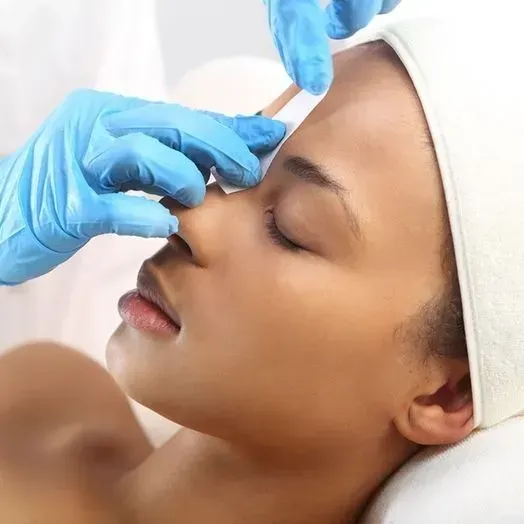 A woman with a towel on her head is getting a facial treatment
