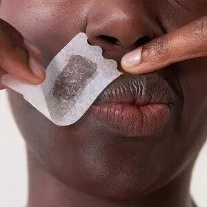 A close up of a person holding a piece of paper to their nose