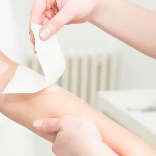A person is applying wax to another person 's arm