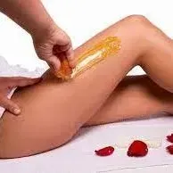 A woman is getting her legs waxed by a man
