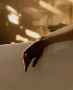 A woman 's hand is reaching out of a bathtub