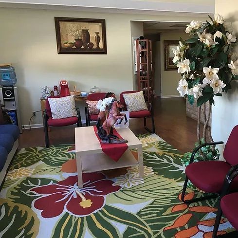 A living room with a rug , chairs , a coffee table and a picture on the wall.